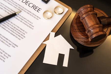divorce decree, wedding rings, gavel, and house paper cutout