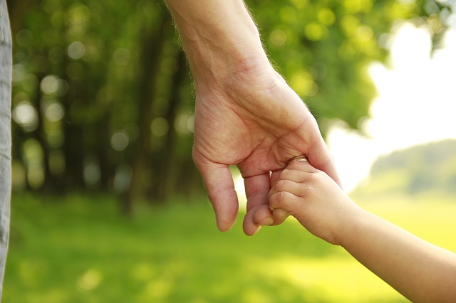 Close-up of parent holding adopted child's hand.
