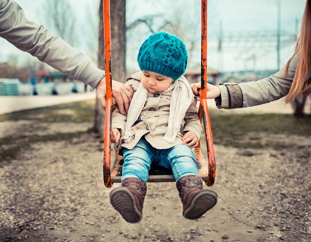 Girl on swing with both parents to symbolize establishing Child Custody Fairly